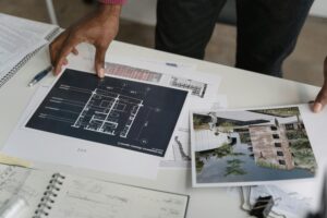 Services Architect hands reviewing architectural blueprints and design documents in an office setting.